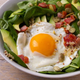 salad with spinach, fried egg, bacon, avocado, and couscous